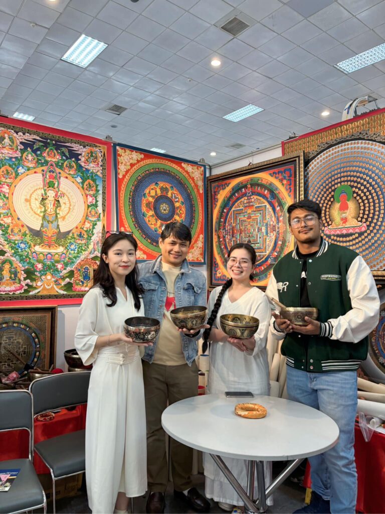 Câu Chuyện Của Chúng Tôi 18 Nhóm người cầm bát với tranh nghệ thuật phía sau.