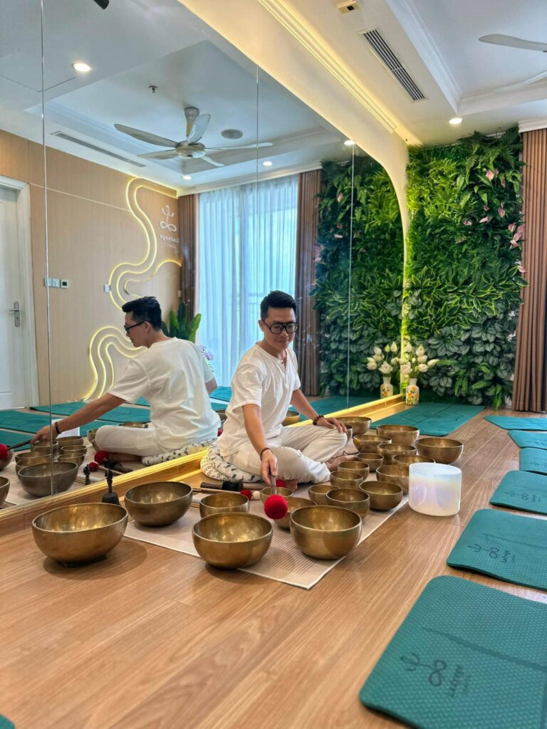 Thiền Chuông Của Madahuma và Ladyoga 15 Người ngồi thiền với bát âm thanh trong phòng yoga.