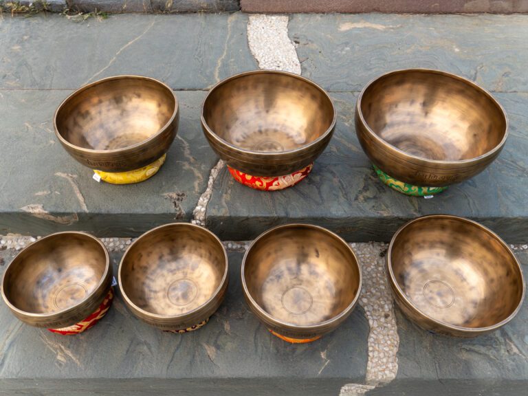 Bát hát Tây Tạng đặt trên đá xám. Bộ 7 Chuông Full Moon Hệ Vedic 17-28cm – By Santa Ratna Shakya