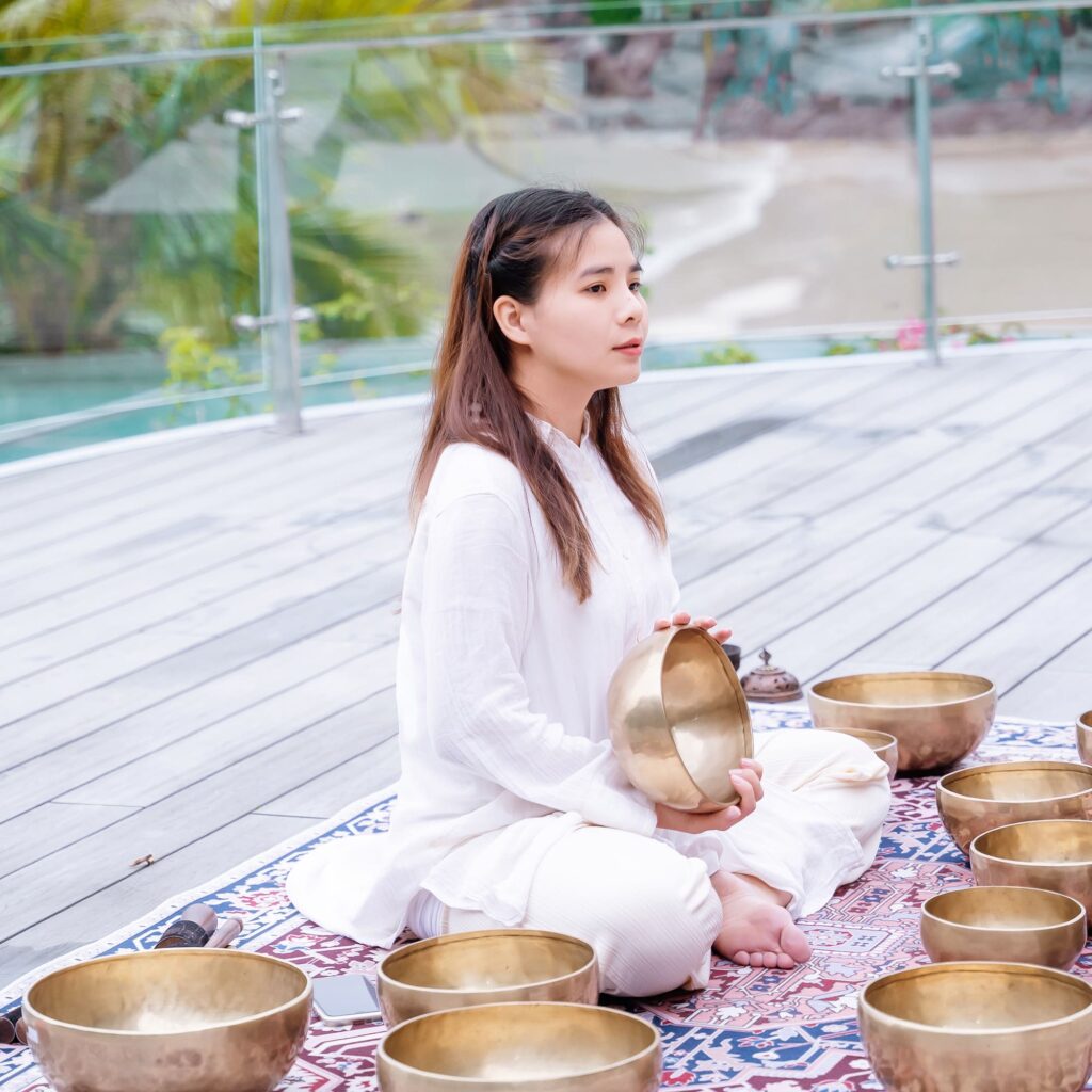 Người phụ nữ thiền với chuông xoay himalaya ngoài trời