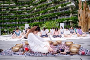 Trị Liệu Chuông Xoay Và Yoga Tại Cát Bà 11 Nhóm người ngồi thiền ngoài trời.