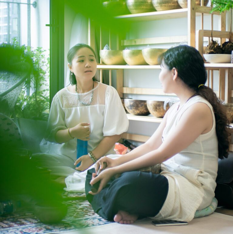 Khóa Học Gieo Duyên Cùng Chuông Xoay Himalaya 17-18/08/2024 46 Hai phụ nữ trò chuyện trong cửa hàng cây xanh.