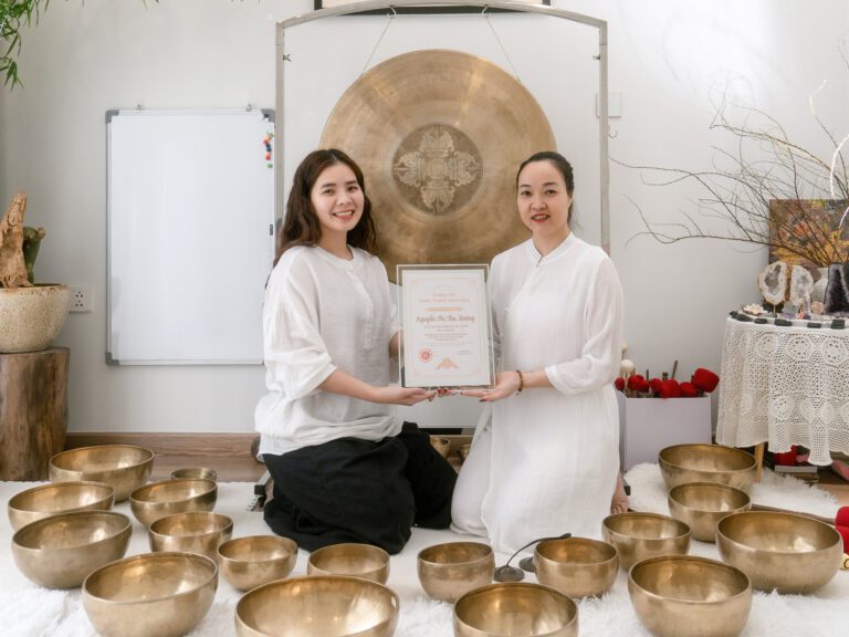 Hai phụ nữ cầm bằng chứng nhận âm thanh trị liệu.