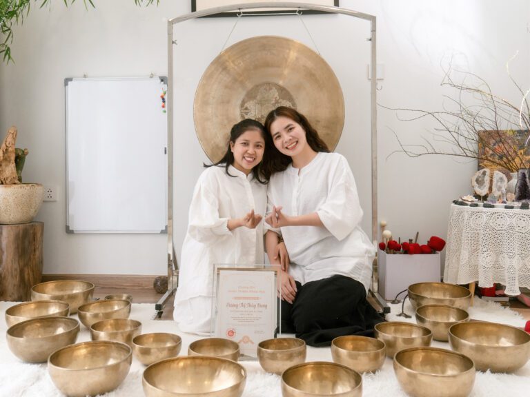 Hai phụ nữ ngồi với chén hát đồng