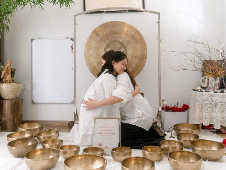 Hai phụ nữ mang thai ôm nhau trước chuông gió.