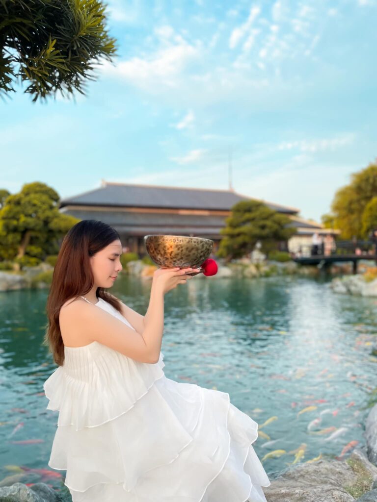 Người phụ nữ cầm bát đồng bên hồ nước.