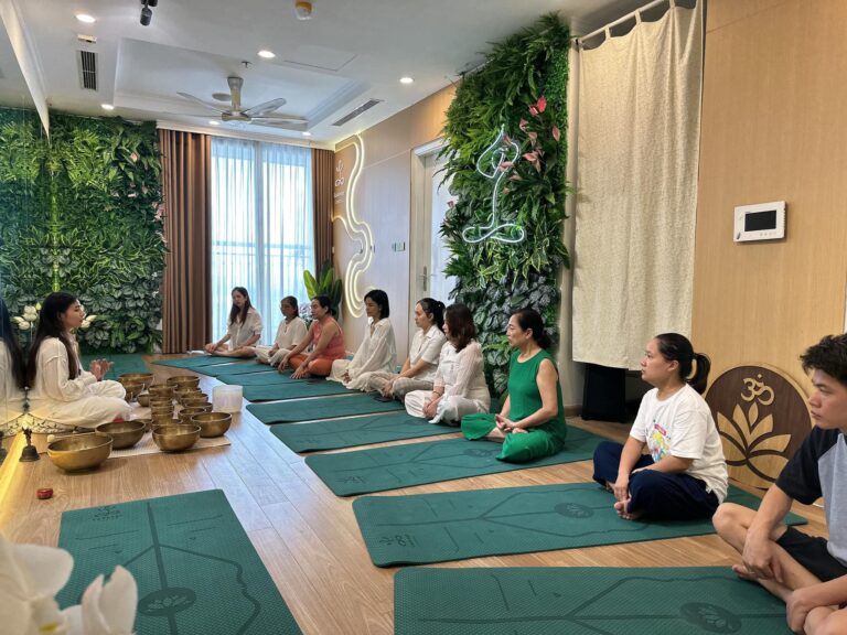 Lớp thiền trong phòng yoga với nhiều người tham gia.