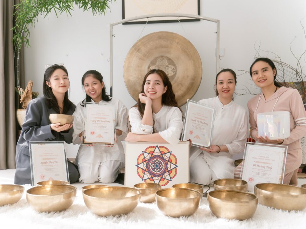 Nhóm phụ nữ cầm bằng, bên chiêng và bát đồng