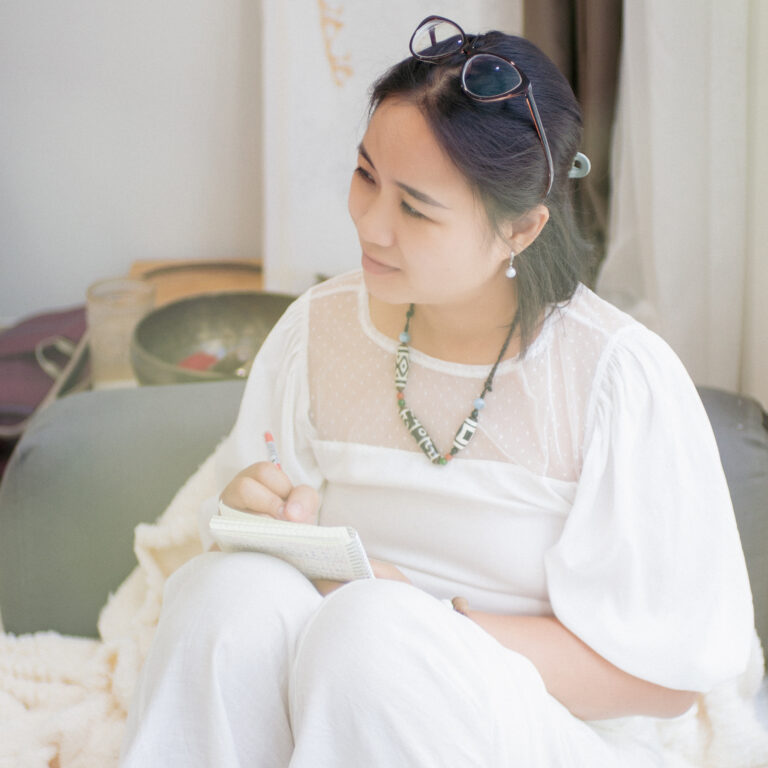 Người phụ nữ viết sổ trong phòng sáng.