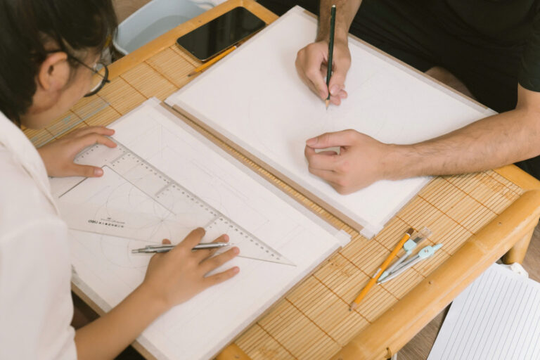 Học sinh vẽ bản vẽ kỹ thuật trên bàn.