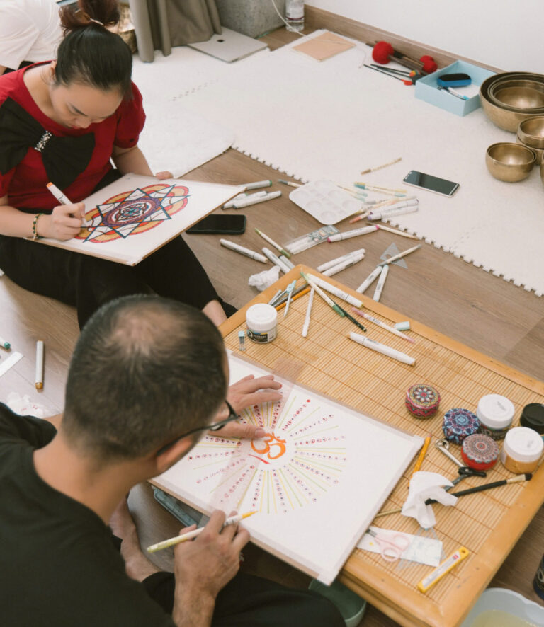 Người vẽ tranh mandala bằng bút màu và giấy.