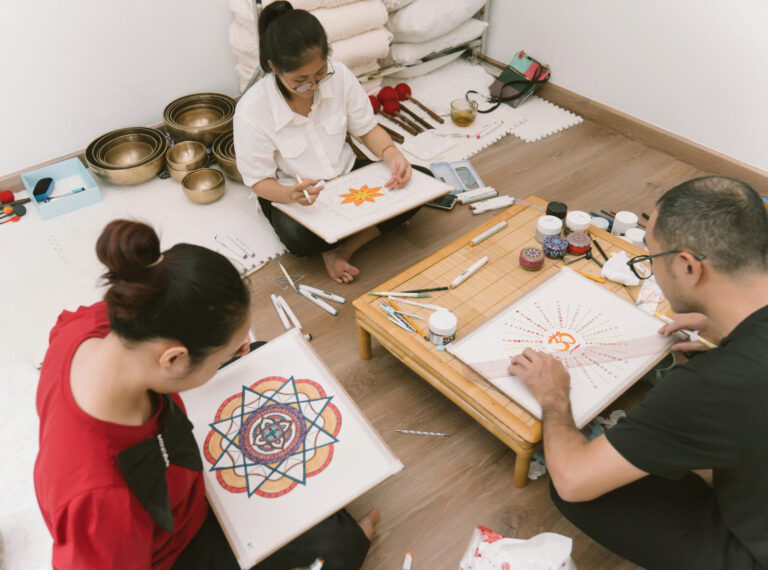 Ba người vẽ tranh mandala trong phòng.