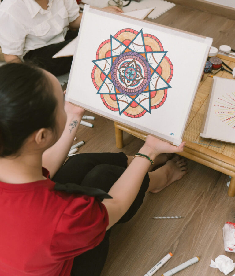 Người phụ nữ cầm tranh mandala đầy màu sắc.